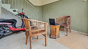 Un escalier avec des rampes en métal, un scooter rouge et deux chaises en bois, dont l’une porte un ordinateur portable.