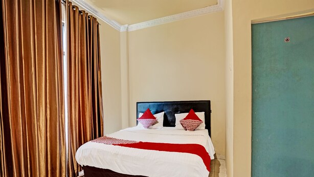 Une chambre d’hôtel avec un lit, des rideaux et une porte.