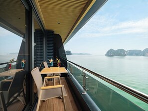 A dining area with a table and chairs, a view of the water, and a wooden ceiling.