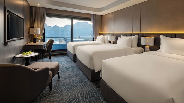 A hotel room with two beds, a desk, a chair, and a view of the sea. - Doria Cruise (Tuan Chau)