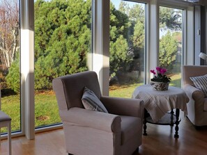A room with a large window, a chair, a small table with a flower pot, and another chair. - 5 Star Holiday Home in Mellbystrand (Mellbystrand)