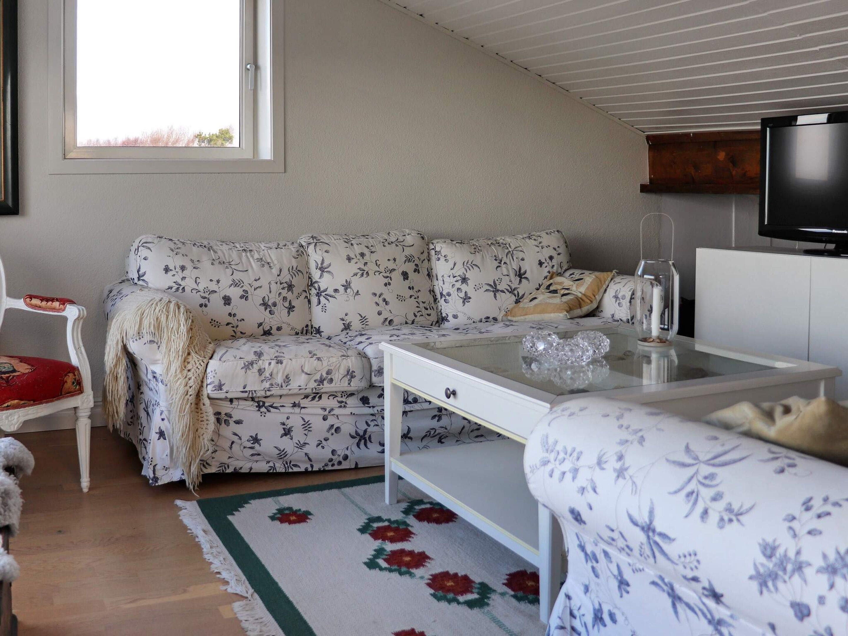 Un salon avec un canapé, une table basse, un téléviseur et une fenêtre.
