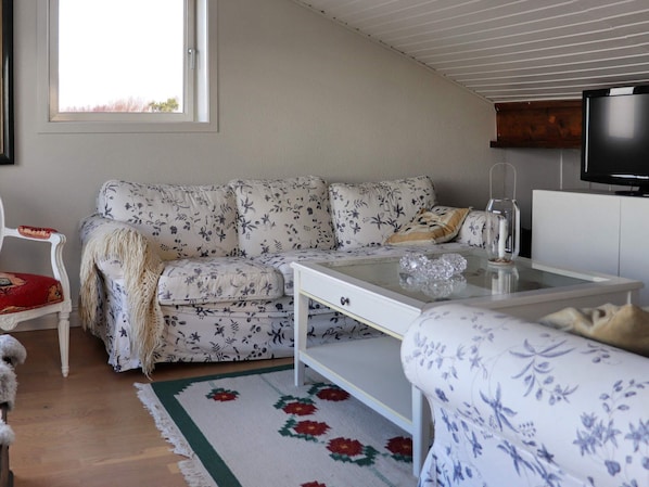 Un salon avec un canapé, une table basse, un téléviseur et une fenêtre.