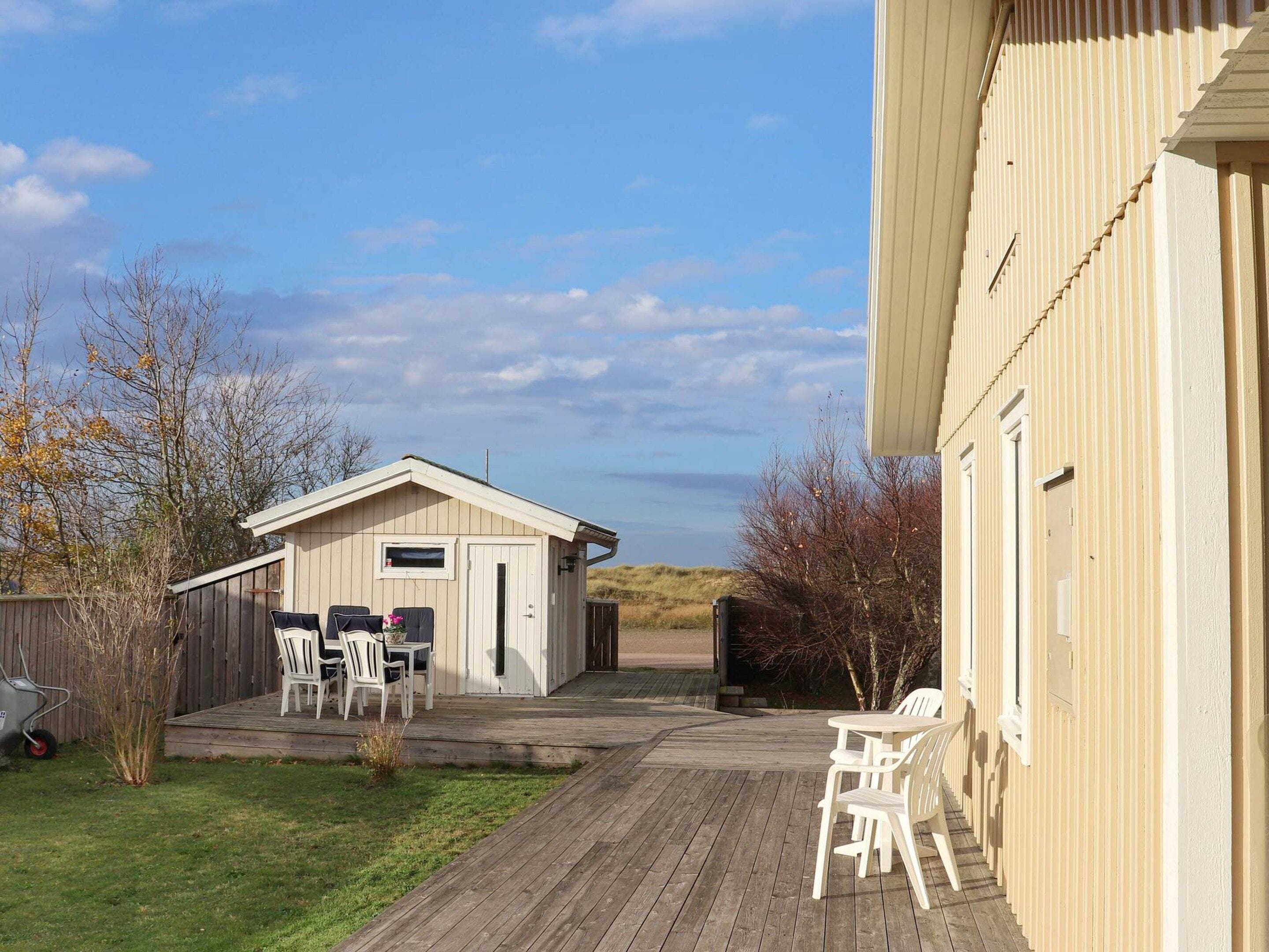 A wooden deck with outdoor furniture, a small shed, and a building with a sloped roof.