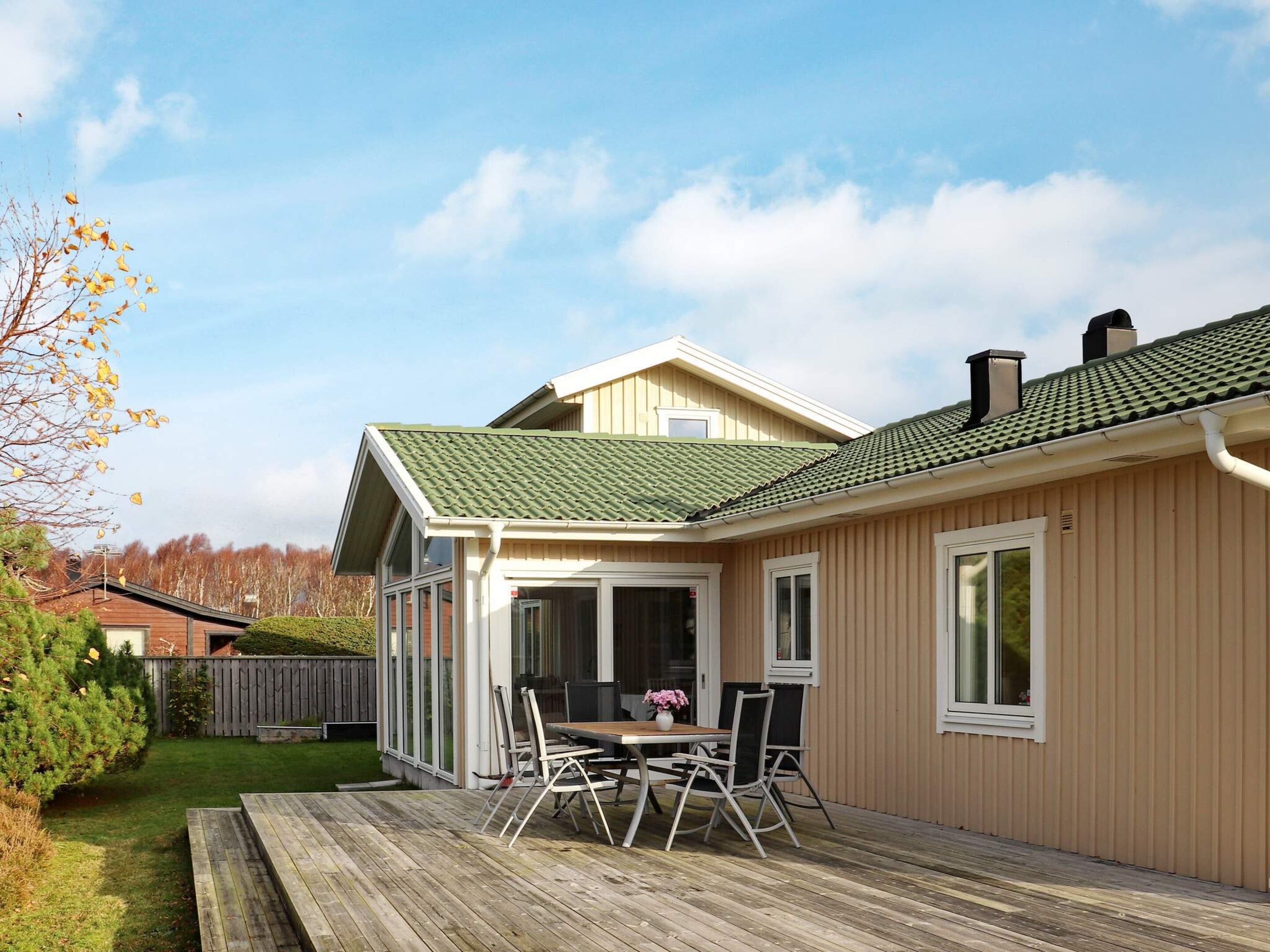 A residential property with a deck, a dining area with chairs, and a large window.