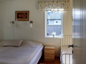 A bedroom with a bed, bedside lamps, a window with a view, a wooden nightstand, and a door. - 5 Star Holiday Home in Mellbystrand (Mellbystrand)
