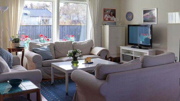 A living room with a sofa set, a television, and a window with curtains. - 5 Star Holiday Home in Mellbystrand (Mellbystrand)