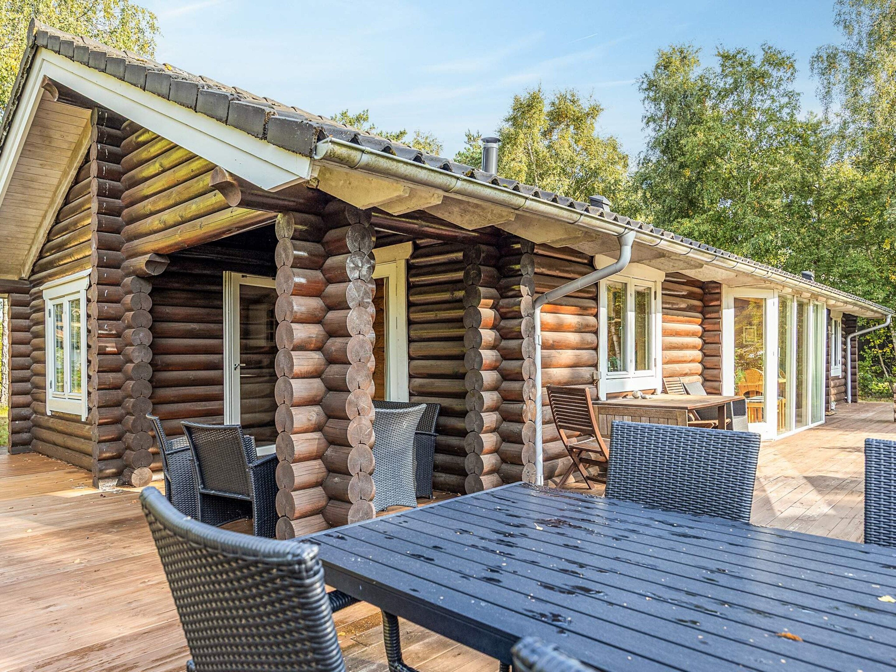 A log cabin with a covered patio area featuring outdoor furniture.