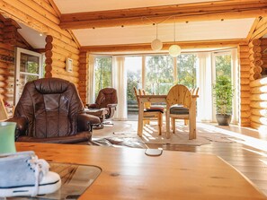 A log cabin interior with a dining area, leather chairs, a wooden table, and a potted plant. - 7 Person Holiday Home in Hadsund (Hadsund)