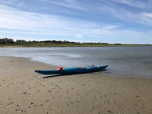 Um caiaque numa praia arenosa, com águas calmas e céu limpo.
