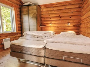 A wooden cabin room with a bed, a window, and a wall-mounted light fixture. - 7 Person Holiday Home in Hadsund (Hadsund)