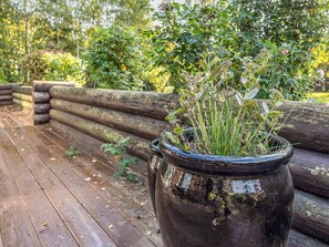A rustic wooden bench with a large, weathered planter filled with green plants. - 7 Person Holiday Home in Hadsund (Hadsund)