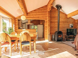 A log cabin interior with a dining area, wooden chairs, a fireplace, and a television. - 7 Person Holiday Home in Hadsund (Hadsund)