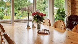 Une table à manger en bois, des chaises, un vase de fleurs et des bougeoirs.