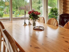 A wooden dining table with chairs, a vase with flowers, and candle holders.