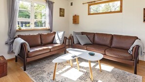 Un salon avec un canapé en cuir marron, une petite table blanche et un tapis à motifs.