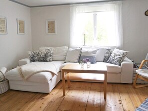 A living room with a white sofa, a wooden coffee table, and a window with curtains. - 6 Person Holiday Home in Hallabro (Hallaröd)
