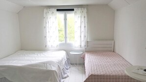 A bedroom with two beds, a small round table, and a window with curtains. - 6 Person Holiday Home in Hallabro (Hallaröd)