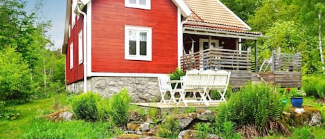 Ein rotes Haus mit Stein Fundament, weißen Fenstern und einer Veranda mit weißen Stühlen.