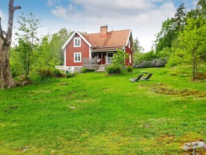 A red house with a porch, surrounded by a grassy yard and trees. - 6 Person Holiday Home in Hallabro (Hallaröd)