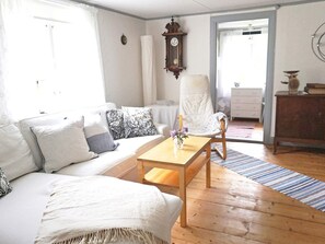 A living room with a sofa, a wooden coffee table, a chair, and a dining area with a table and chairs.