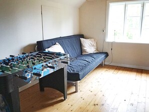 A room with a foosball table, a sofa, and a window with a view of greenery. - 6 Person Holiday Home in Hallabro-by Traum (Hallaröd)