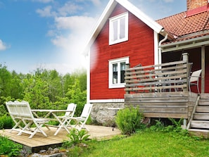 A red house with a wooden deck and outdoor seating. - 6 Person Holiday Home in Hallabro (Hallaröd)