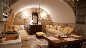 Una sala de estar acogedora con una pared de piedra, un banco de madera, una mesa de comedor con individuales y un sofá con cojines estampados.