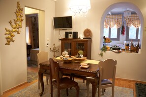 Une salle à manger avec une table en bois, des chaises, un téléviseur et un lustre.
