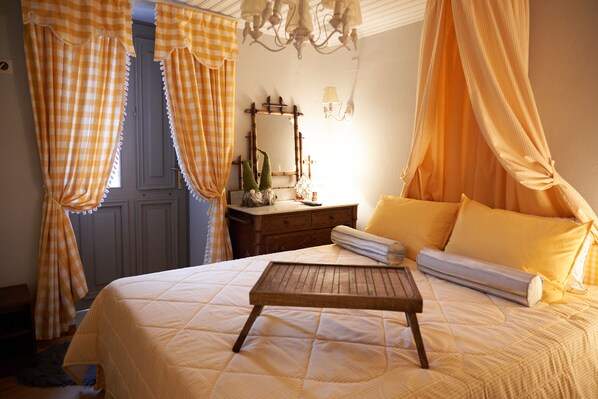 Une chambre à coucher avec un lit, un plateau en bois, un miroir et des rideaux.