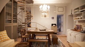 Un salón acogedor con una mesa de comedor de madera, un banco y una escalera que sube a un altillo.