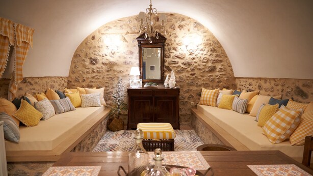 Una habitación acogedora con pared de piedra, un banco de madera y una mesa con cubierta de vidrio decorativa.