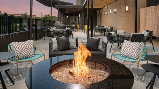 An outdoor patio area with round tables, chairs, and a central fire pit. - SpringHill Suites by Marriott Cincinnati Mason (Mason)