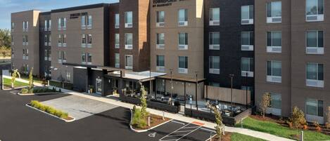 A multi-story hotel with a modern design, labeled "Townplace Suites by Marriott," featuring a parking lot with handicapped accessibility.