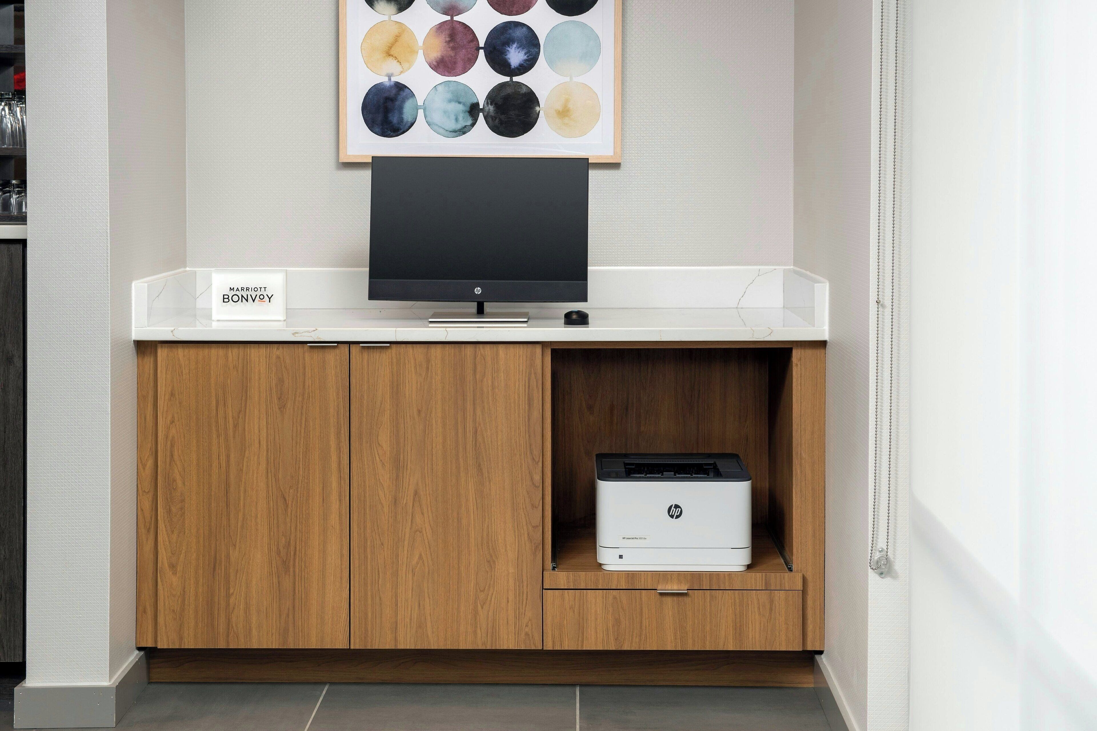 Ein Hotelzimmer mit einem Holzkasten, einem Flachbildfernseher und einem HP-Drucker.