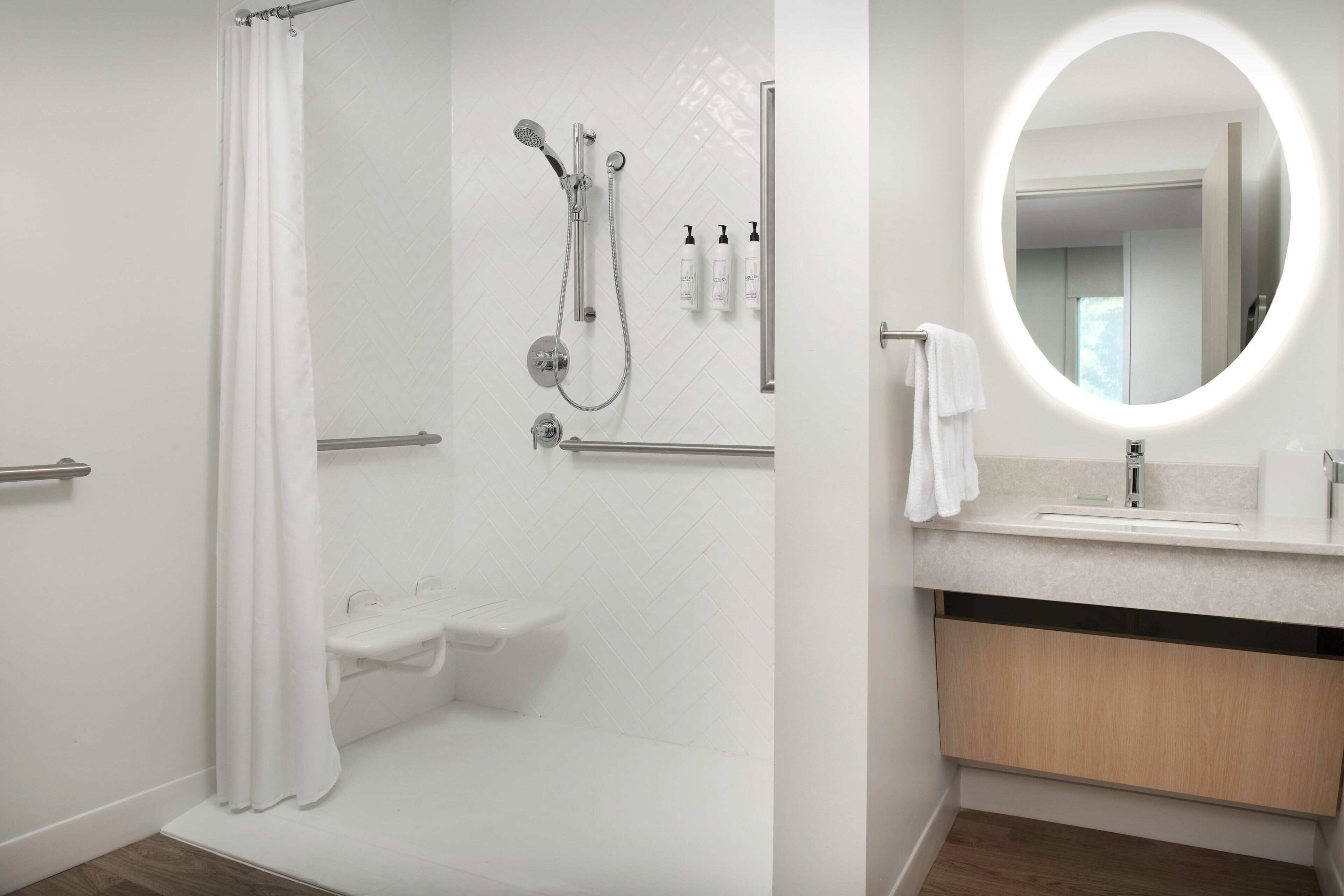Un baño moderno con ducha, inodoro y tocador con espejo.