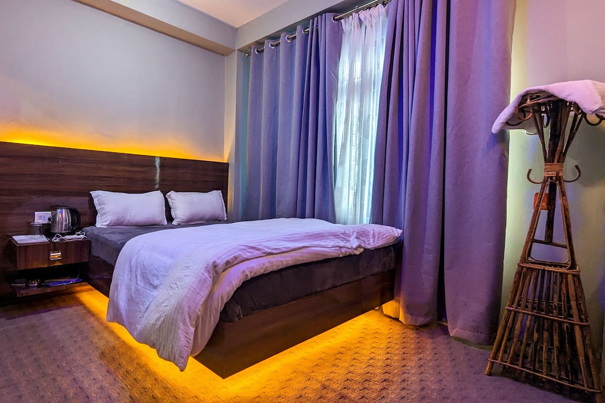 A hotel room with a bed, bedside table, and a lamp.