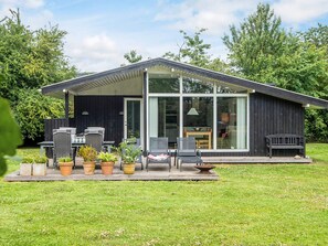 A modern house with a patio area featuring outdoor furniture and potted plants.