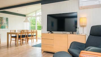 Ett modernt vardagsrum med en platt-TV, trämöbler och ett stort fönster.