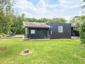 A small, dark-colored building with a tiled roof, a window, and a door. - 5 Person Holiday Home in Odder (Odder)