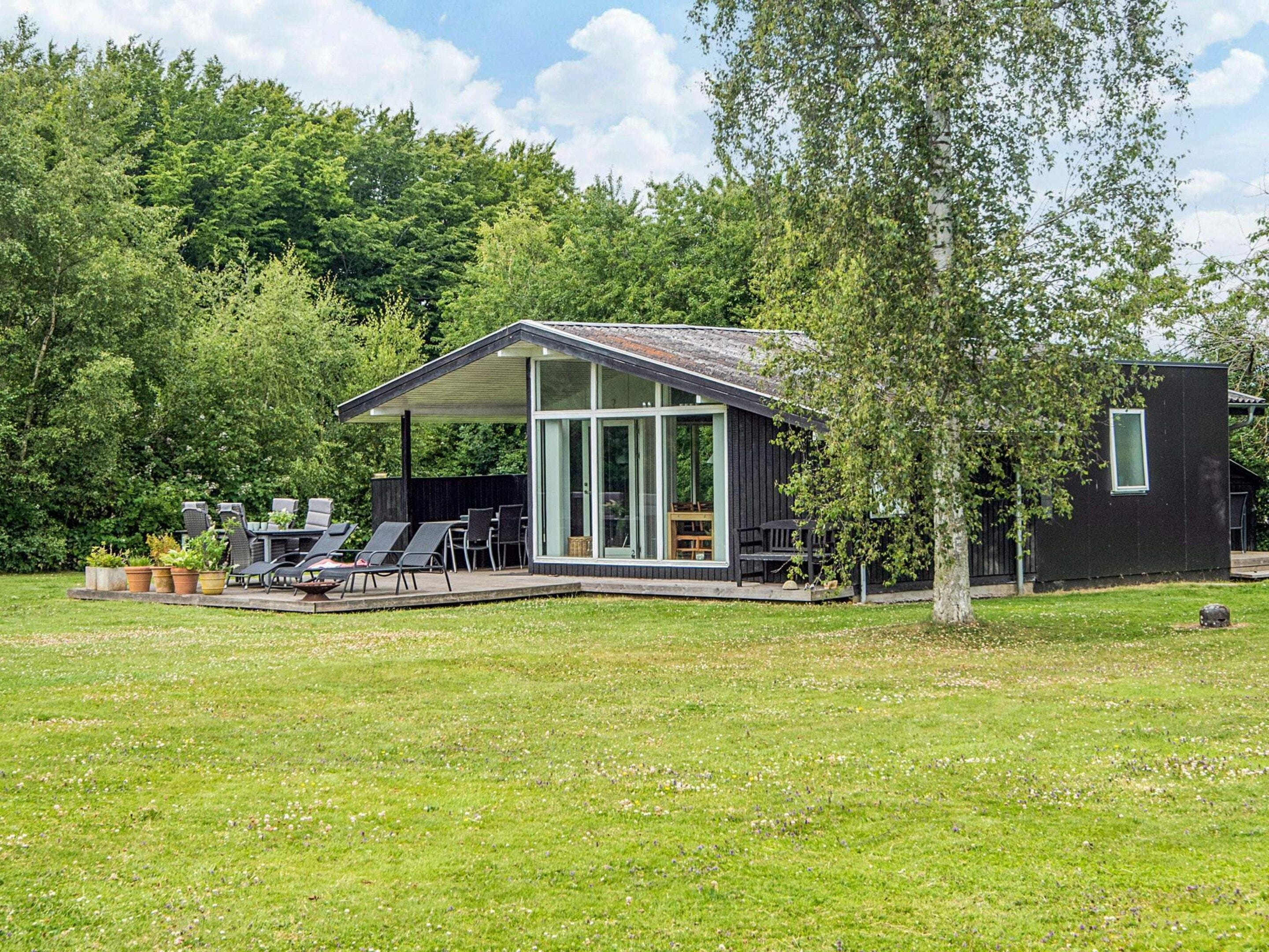 A modern house with a covered patio, outdoor seating, and a lawn.