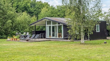 A modern house with a covered patio, outdoor seating, and a lawn.