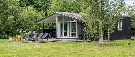 A modern house with a covered patio, outdoor seating, and a lawn.