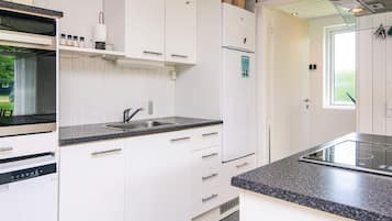 A modern kitchen with white cabinetry, a built-in oven, a sink, and a stove.