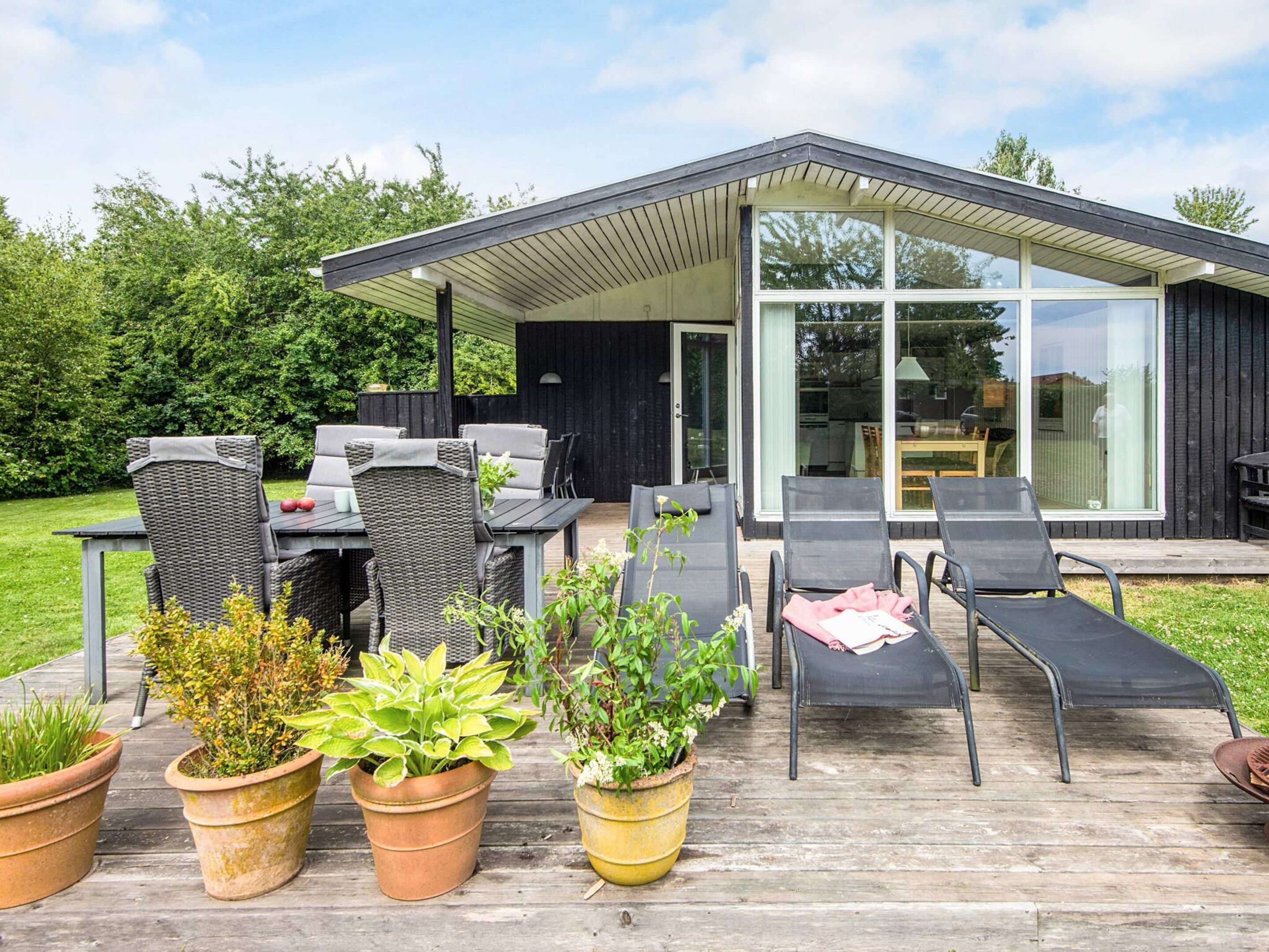 An outdoor patio with a dining table and chairs, lounge chairs, and potted plants.