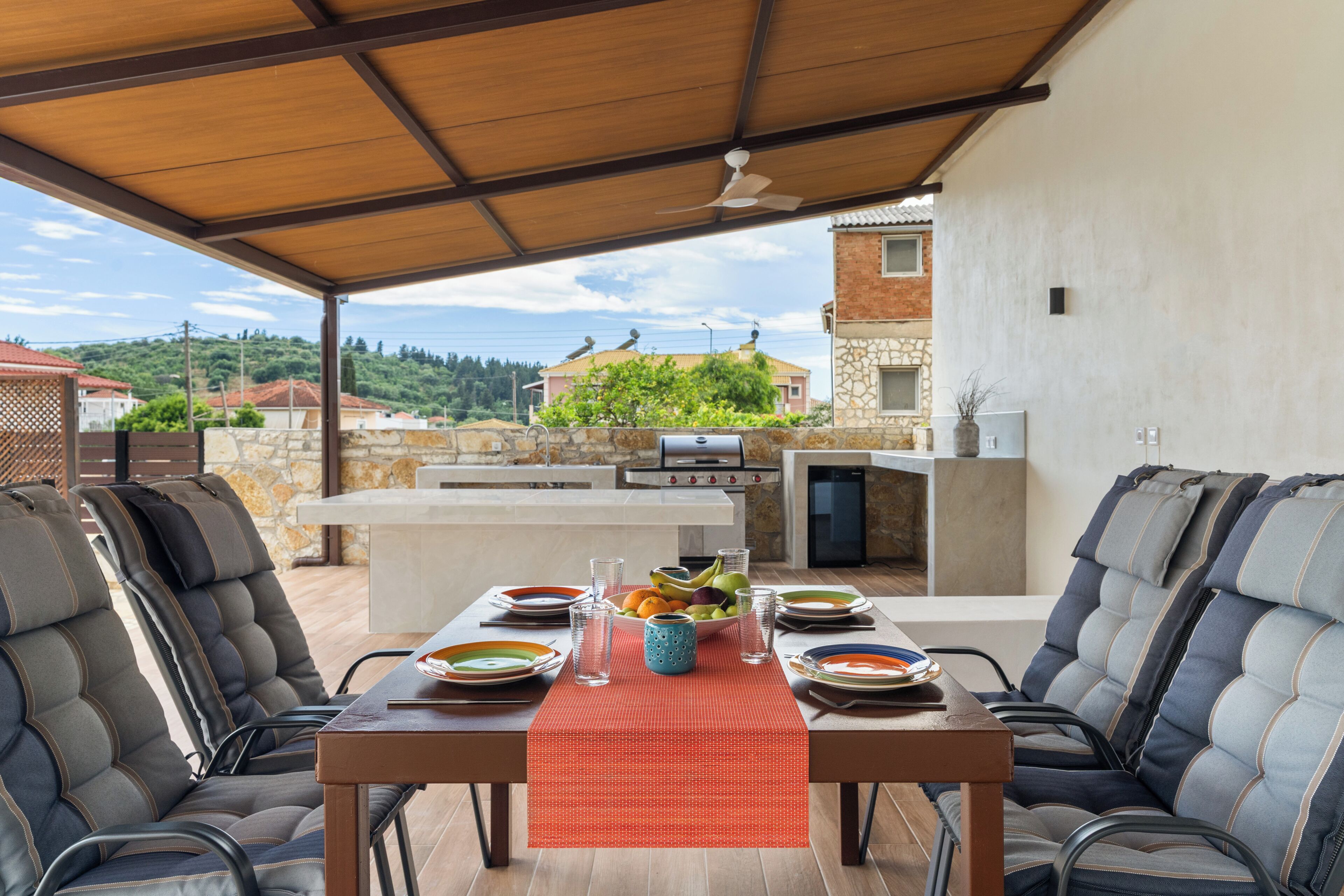 Un espace extérieur aménagé pour les repas, avec une table pour deux, un barbecue et une vue sur le quartier environnant.