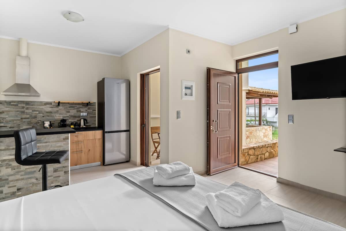 Une chambre d’hôtel moderne dotée d’une kitchenette, d’un lit avec une grande fenêtre et d’une vue sur l’extérieur.