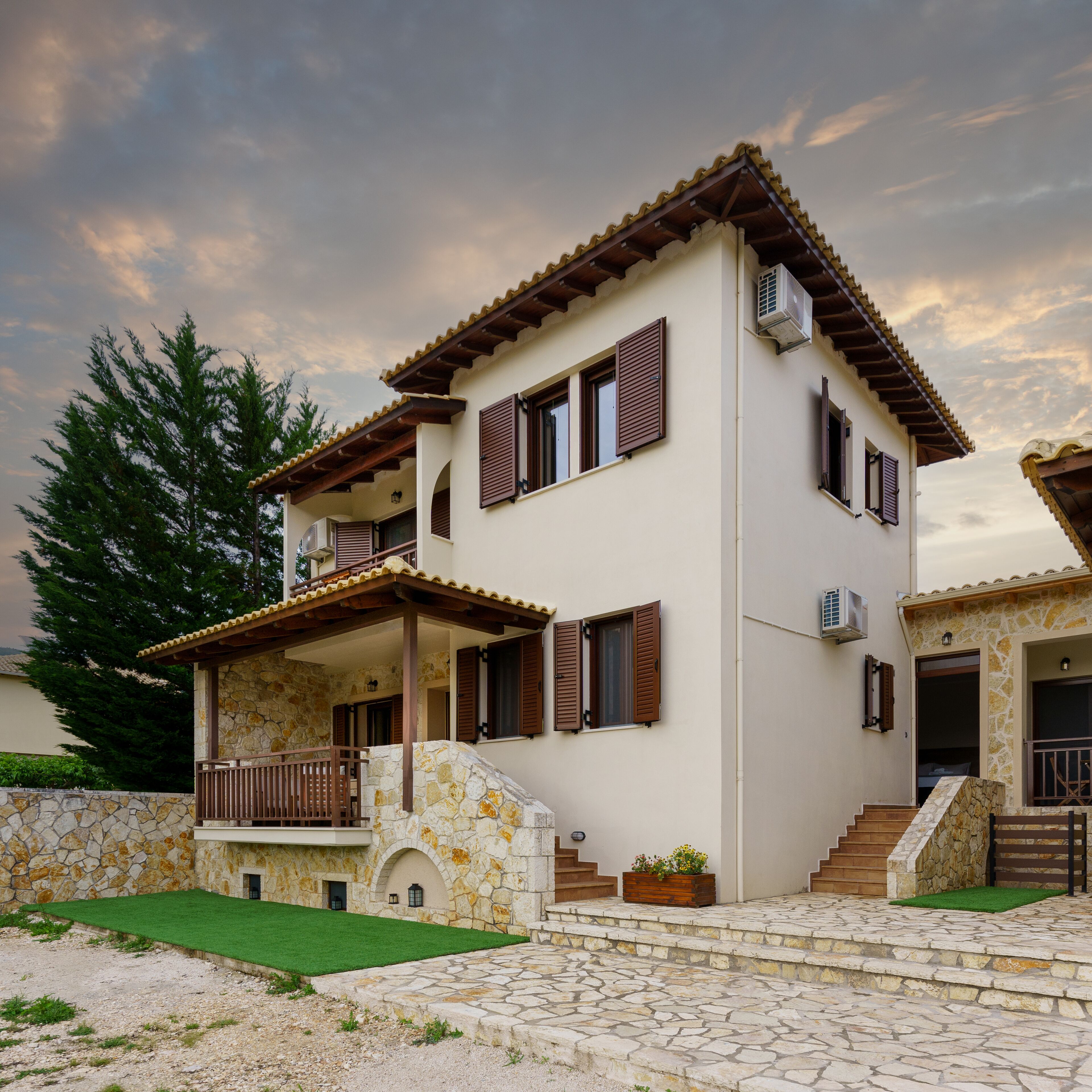 A two-story house with a stone facade, wooden shutters, and a balcony.