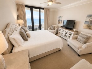Une chambre d’hôtel avec un grand lit, un canapé, une télévision et un balcon donnant sur la mer.