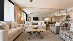 A spacious living room with a sofa, a coffee table, and a patterned armchair. - West 1003 at Eden Condominiums Gulf Front Condo with Stunning Views! (Pensacola)